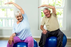 Portrait of smiling senior man and woman exercising at health club