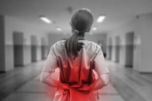 Nurse touching hurting back in red lumbar area with hands in black and white as intense pain concept
