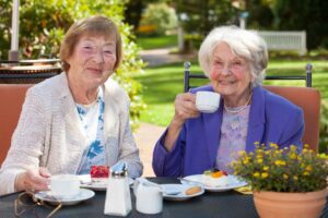 Close up Two Happy Senior Women Looking at the Camera While Having Coffee Time at the Garden Table.