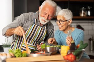 Modern and harmonious couple prepares their favorite recipe and shares with their friends via video call, fun and domestic life of pensioner